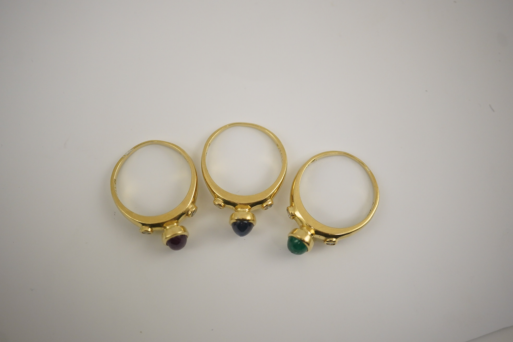 A suite of three modern 18k gold and gem set rings